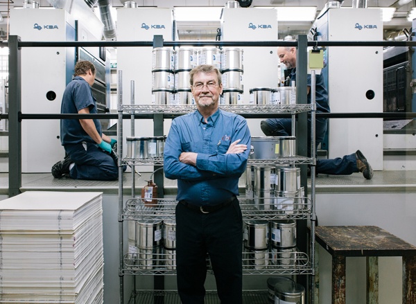 CBN employee smiling with arms crossed, standing in front of printing machine